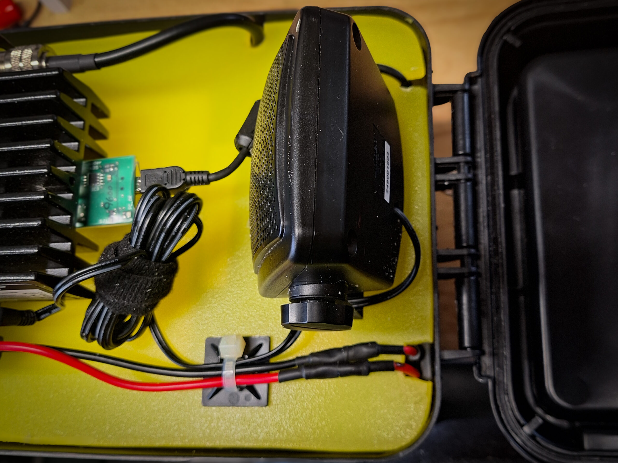 Detail image of yellow cutting board with radio, and speaker mounted. cabling is run and tied down with zip ties and zip tie anchors. RA board installed on radio and usb cable installed.