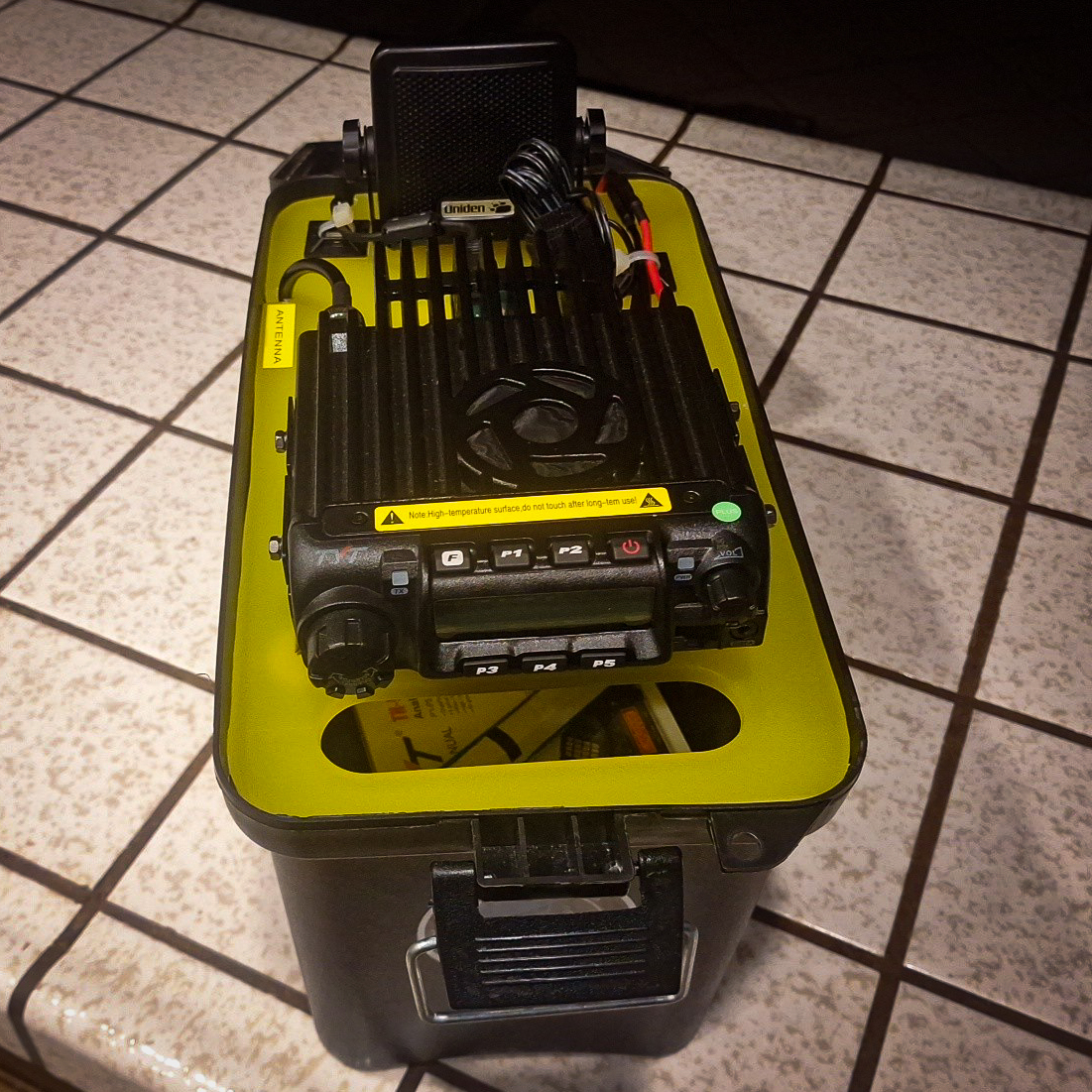 Tactical Winlink Gateway top front view. radio and speaker mounted on a yellow cutting board and fit into the top of a black utility box.
